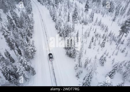 Vue aérienne d'une voiture traversant la forêt boréale couverte de neige, Akaslompolo, Lapalnd finlandais, Finlande, Scandinavie, Europe Banque D'Images