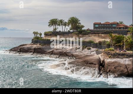 Côte spectaculaire de Costa Adeja, avec l'océan Atlantique s'écrasant contre le promontoire rocheux, et des palmiers exotiques Banque D'Images