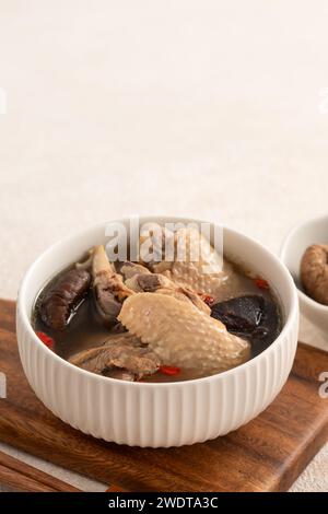 Délicieuse soupe de poulet aux champignons shiitake take taïwanais dans un bol sur fond de table blanc. Banque D'Images