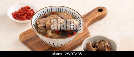 Délicieuse soupe de poulet aux champignons shiitake take taïwanais dans un bol sur fond de table blanc. Banque D'Images