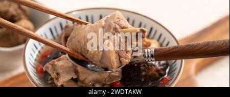 Délicieuse soupe de poulet aux champignons shiitake take taïwanais dans un bol sur fond de table blanc. Banque D'Images