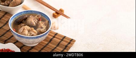 Délicieuse soupe de poulet aux champignons shiitake take taïwanais dans un bol sur fond de table blanc. Banque D'Images