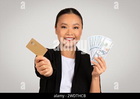 Femme d'affaires asiatique souriante offre un choix entre l'argent comptant et la carte de crédit Banque D'Images