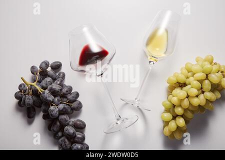 Les verres à vin avec des boissons blanches et rouges sont entre les raisins. Banque D'Images