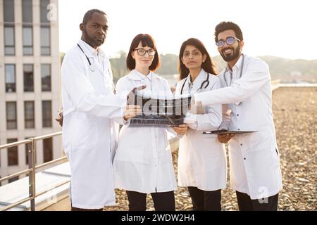 Des médecins multiculturels discutent de la tomodensitométrie du patient en dehors de l'hôpital. Banque D'Images