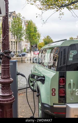 Recharge hybride rechargeable électrique Land Rover Defender sur le côté du canal à Keizergracht à Amsterdam, Hollande. Banque D'Images