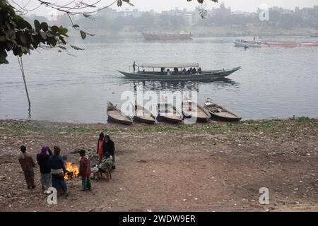 Dhaka, Bangladesh. 22 janvier 2024. Les travailleurs entourent un feu de bon feu pour se réchauffer sur la rivière Buriganga en raison du temps brumeux à Dhaka. Dhaka enregistre la température la plus basse de la saison 12,5°C le 22 janvier 2024 matin. Crédit : SOPA Images Limited/Alamy Live News Banque D'Images