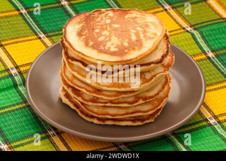 Crêpes de blé frais sur assiette grise. Tas de pancakes cuits au four. Tableau avec arrière-plan Checker vert éclatant. Banque D'Images