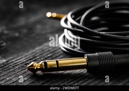 Câble audio avec connecteurs Jack et Mini Jack, sur une table sombre, vue rapprochée Banque D'Images