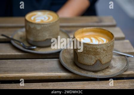 Café blanc plat servi dans des tasses en céramique faites à la main photographiées à Budapest, Hongrie Banque D'Images