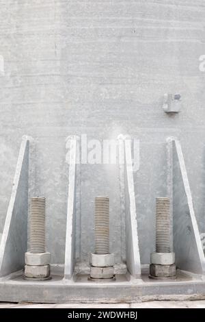 Boulons et écrous sur une plaque d'acier. Plusieurs paires de boulons argentés sont fermement fixées sur la base métallique ronde de la colonne à la base en béton du WITH Banque D'Images