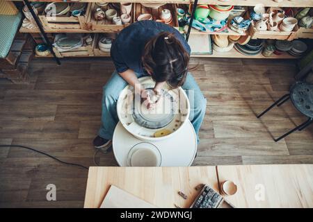 Une femme céramiste à une roue de poterie dans un atelier Banque D'Images