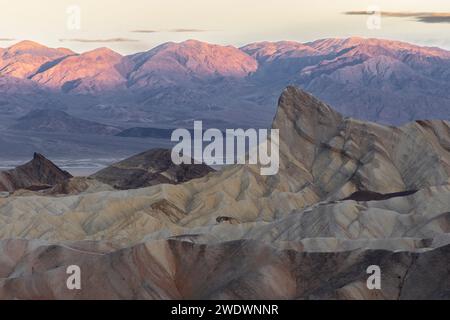 Lever de soleil avec lueur de montagne. Formations rocheuses au premier plan. Zabriskie point, Vallée de la mort Banque D'Images