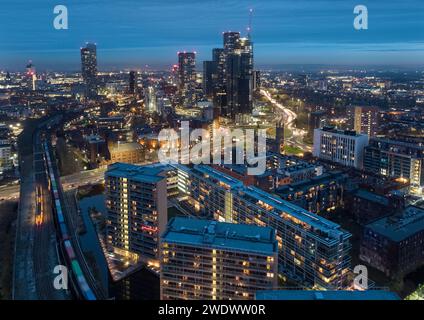 Photo aérienne au crépuscule à l'heure de pointe d'un train de marchandises en route pour Manchester avec Mancunian Way, Castlefield et New Jackson avec le centre-ville derrière Banque D'Images