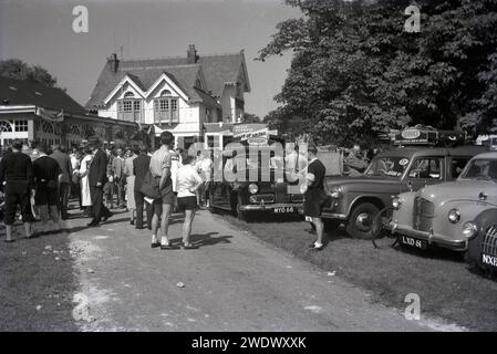 1952, histoire, rassemblement de personnes au début d'une étape de la course cycliste amateur Daily Express Tour of Britain, Angleterre, Royaume-Uni. Vu sur la photo les voitures officielles et un véhicule de service, avec bagages sur la galerie de toit. Banque D'Images
