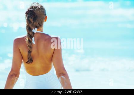Jeune femme assise au bord de mer. Vue arrière Banque D'Images