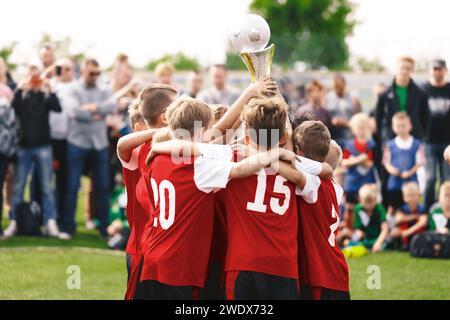 Des enfants heureux remportant un tournoi sportif. Les enfants dans les équipes sportives gagnent des trophées sur les tournois Schoolboys debout dans un cercle et tenant le trop d'or Banque D'Images