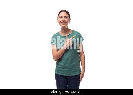 jeune femme aux cheveux noirs dans un t-shirt de base vert avec surprise raconte la nouvelle Banque D'Images