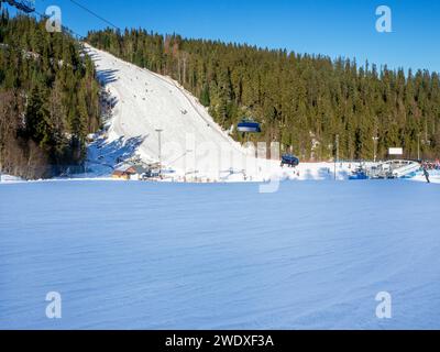 Piste de ski raide, télésièges, skieurs et snowboarders dans la station de ski Bialka Tatrzanska en Pologne en hiver dans la basse lumière de décembre. Grand espace de copie dans le Banque D'Images