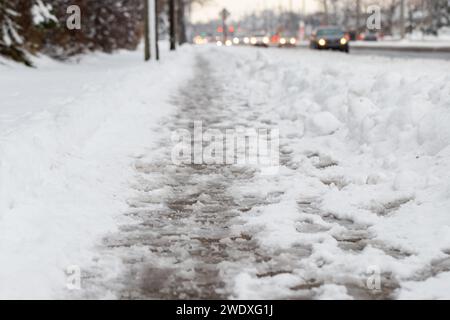 Route d'hiver avec fonte de neige salée. Gros plan du trottoir avec de la neige fondante le jour de la neige. Banque D'Images