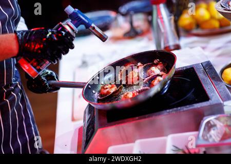 les huîtres dans une poêle cuisent le chef, le feu. Photo de haute qualité Banque D'Images