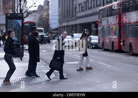 Les navetteurs, y compris l'homme portant une mallette, font la queue pour traverser Tottenham court Road un matin d'hiver, Londres, Angleterre, Royaume-Uni Banque D'Images