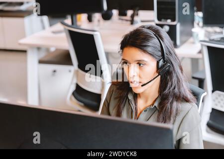 Représentant du service clientèle féminin dédié avec micro-casque/oreillette sur un poste de travail. Banque D'Images