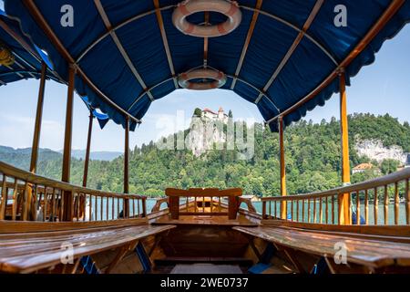 Vue à travers le bateau traditionnel Pletna au château de Bled au sommet de la roche avec la forêt autour, Slovénie, Bled Banque D'Images