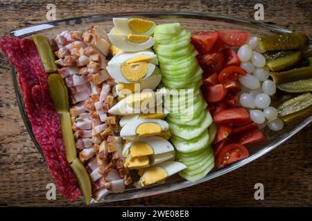 bol doublé plein de nourriture, oeuf, bacon, concombre, salami, tomate, oignon sur un fond en bois. Banque D'Images