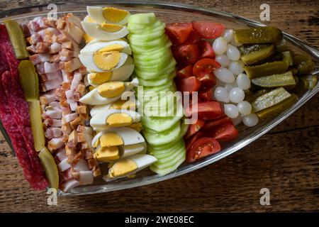 bol doublé plein de nourriture, oeuf, bacon, concombre, salami, tomate, oignon sur un fond en bois. Banque D'Images