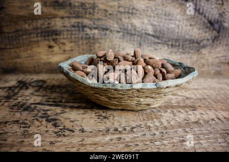 amandes dans un bol en céramique sur un fond en bois, vue de dessus. Banque D'Images