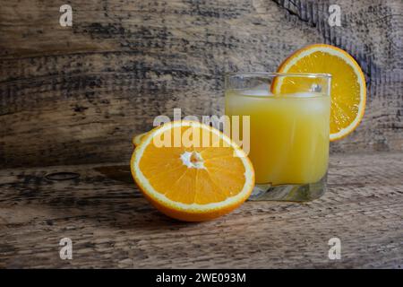 jus d'orange dans un verre avec de la glace, une paille et un morceau d'orange. Banque D'Images