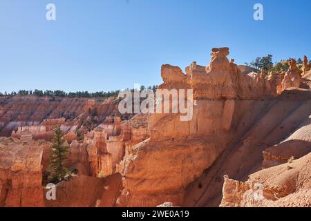 Une formation rocheuse au bord de l'amphithéâtre de Bryce Canyon. Des hoodos colorés et des couches blanches sont vus au loin. Banque D'Images
