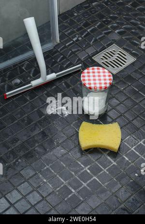 Bicarbonate de soude, éponge et lingette de douche sur le sol de douche carrelé, nettoyage écologique Banque D'Images