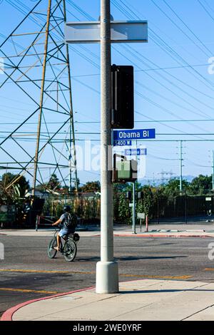 Homme roulant son vélo devant un panneau pour Obama Boulevard dans le quartier de Baldwin Hills/Crenshaw à Los Angeles Banque D'Images