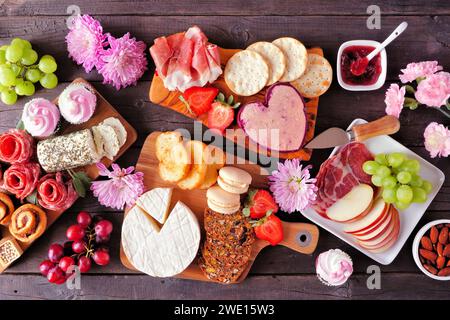 Scène de table de charcuterie de thème de fête des mères sur un fond de bois sombre. Assortiment de fromages, viandes, fruits et hors-d'œuvre sucrés. Vue de dessus. Banque D'Images