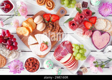 Scène de table de charcuterie de thème de fête des mères sur un fond de bois blanc. Variété de fromages, viandes, fruits et bonbons. Vue de dessus. Banque D'Images