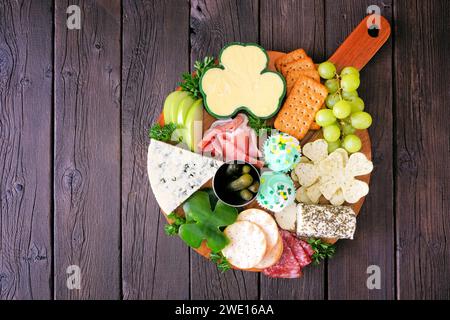 Planche de charcuterie à thème de la Saint-Patrick sur fond de bois. Variété de fromages, viandes, fruits et légumes hors-d'œuvre. Vue de dessus. Banque D'Images