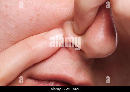 Femme qui fait sauter le bouton sur son nez, gros plan Banque D'Images