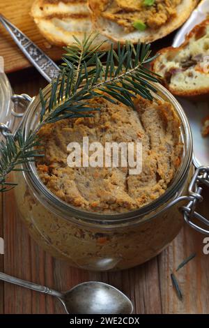 Pâté dans un pot en verre avec du vin sur un fond en bois Banque D'Images