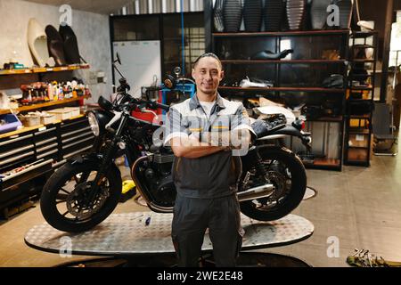 Portrait du propriétaire heureux de l'atelier de réparation de moto debout dans son garage Banque D'Images