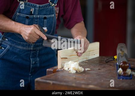 Menuisier travaillant avec de l'équipement sur une table en bois. Menuisier travaillant sur des machines à bois dans un atelier de menuiserie. l'homme travaille dans un atelier de menuiserie. Banque D'Images