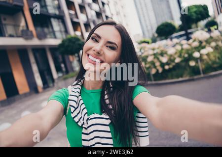 Selfie de jeune fille de blogging enregistrement vidéo pour les abonnés marchant rue à l'extérieur de son complexe résidentiel de ville sur fond Banque D'Images