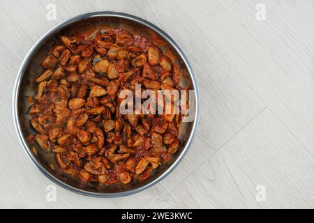 Les coeurs de poulet au persil et aux tomates sont frits dans une poêle en métal sur fond de bois. Cuisine maison ou culinaire. Plat fait maison. Banque D'Images