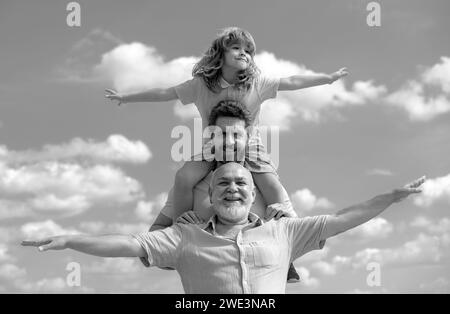 Famille générationnelle.Père, fils et grand-père famille heureuse de plusieurs genration avec les mains levées ou les bras ouverts volant sur le ciel. Banque D'Images