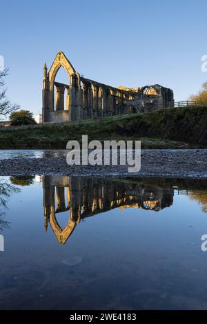 Les ruines du Prieuré de Bolton (alias Bolton Abbey), reflétées dans les eaux encore de la rivière Wharfe, Yorkshire Dales, Royaume-Uni Banque D'Images