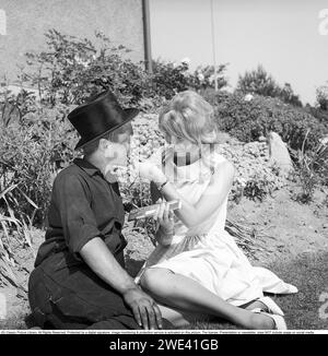 Chocolat Mazetti. Un jeune couple assis sur une journée ensoleillée d'été et elle offre dim un morceau de chocolat de sa barre de chocolat. Suède 1962. Kristoffersson réf CZ54 Banque D'Images