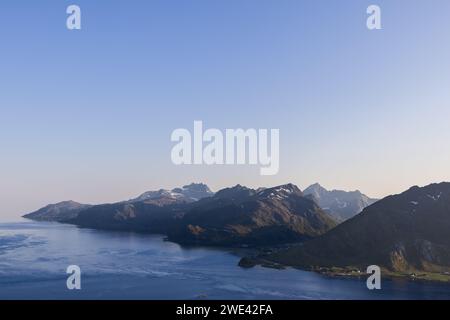 La douce lumière du crépuscule met en valeur les sommets majestueux et les eaux sereines des îles Lofoten, en Norvège, créant une harmonie paisible entre les terres Banque D'Images