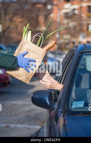 sac en papier avec des fournitures essentielles donné à la personne âgée à la file d'attente du point de distribution alimentaire Banque D'Images