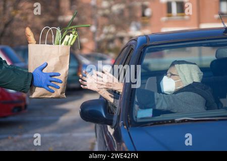 sac en papier avec épicerie remis à la personne âgée nécessiteuse dans le véhicule Banque D'Images